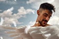 Young man with white wings and a blue sky with white clouds in the background Royalty Free Stock Photo