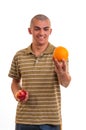 Young man who offers orange instead of red apple Royalty Free Stock Photo