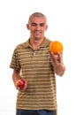 Young man who offers orange instead of red apple Royalty Free Stock Photo