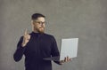 Young man who's looking at screen of laptop has an idea, points finger up and smiles Royalty Free Stock Photo