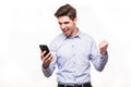 Young man with win gesture and using mobile phone isolated over white background Royalty Free Stock Photo