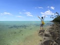 Young man with winner hands up stands on islet in Muri lagoon i