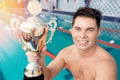 Young man winner in swim pool with champion gold trophy with sun light