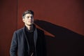 Young Man in a Winter Outfit Leaning on Red Wall Royalty Free Stock Photo