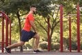 Young man with wireless headphones listening to music while exercising on sports ground Royalty Free Stock Photo