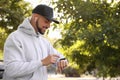 Young man with wireless headphones and smartwatch listening to music in park Royalty Free Stock Photo