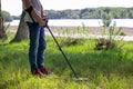 Young man with a wireless metal detector in search of treasure on the river bank