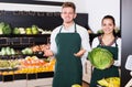 Young man and woman assistants displaying vegetables Royalty Free Stock Photo