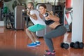 Young man and woman with barbell flexing muscles and making shoulder press squat in gym Royalty Free Stock Photo