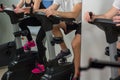 Young man and woman biking in the gym, exercising legs doing cardio workout cycling bikes Royalty Free Stock Photo