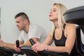 Young man and woman biking in the gym, exercising legs doing cardio workout cycling bikes Royalty Free Stock Photo