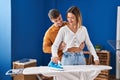 Young man and woman couple hugging each other ironing clothes at laundry room Royalty Free Stock Photo