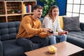 Young man and woman couple playing video game sitting on sofa at home Royalty Free Stock Photo