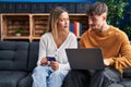 Young man and woman couple using laptop and credit card sitting on sofa at home Royalty Free Stock Photo
