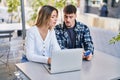 Young man and woman couple using laptop and credit card sitting on table at coffee shop terrace Royalty Free Stock Photo