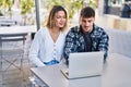 Young man and woman couple using laptop sitting on table at coffee shop terrace Royalty Free Stock Photo