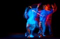 Young man and woman dancing hip-hop in sportive style clothes on dark background at dance hall in mixed neon light Royalty Free Stock Photo