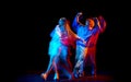 Young man and woman dancing hip-hop in sportive style clothes on dark background at dance hall in mixed neon light Royalty Free Stock Photo