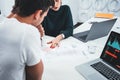 Young man and woman designer sketching a construction project at laptop and drawing plan while working at office