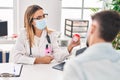 Young man and woman doctor and patient wearing medical mask holding urine test tube at clinic Royalty Free Stock Photo