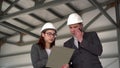 Young man and woman in helmets with documents at a construction site. Bosses in suits are discussing an architecture Royalty Free Stock Photo