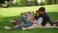 Young man and woman laughing outdoors. Girl and guy sitting on blanket in park Royalty Free Stock Photo