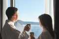 Young man and woman looking out window and holding mugs of coffee, concept of travel or family relationships. Royalty Free Stock Photo