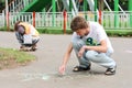 Young man and woman painting on asphalt