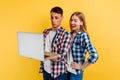 Young man and woman in a plaid shirt, using the laptop on a yellow background Royalty Free Stock Photo