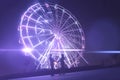 a young man and woman romance love in the night in amusement park near ferris wheel