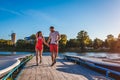 Young man and woman running along summer river dock. Couple having fun at sunset holding hands. People relaxing Royalty Free Stock Photo