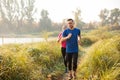 Young man and woman running along the trail trough tall grass Royalty Free Stock Photo