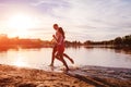 Young man and woman running on summer river bank. Couple having fun at sunset. Guys chilling Royalty Free Stock Photo