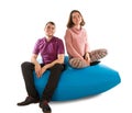 Young man and woman sitting on blue beanbag sofa Royalty Free Stock Photo