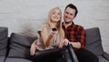 Young man and woman are sitting on the couch, watching TV