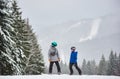 Young man and woman snowboarder standing on high snow-covered slope and looking at each other. Snowfall on background. Royalty Free Stock Photo