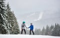 Young man and woman snowboarder standing on high snow-covered slope and looking at each other. Snowfall on background. Royalty Free Stock Photo