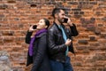 Young man and woman stand nearby back to back, talking on their cell phones Royalty Free Stock Photo