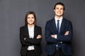 Concept of partnership in business. Young man and woman standing back-to-back with crossed hands against gray background Royalty Free Stock Photo