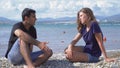 Young man and woman talking on beach on sunny day. Media. Couple is relaxing on beach and talking on background of Royalty Free Stock Photo