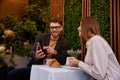 Young man and woman talking using mobile phone having business meeting in cafe Royalty Free Stock Photo