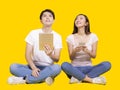 Young man and woman using tablet computer and smartphone.Isolated on yellow background.Look above Royalty Free Stock Photo
