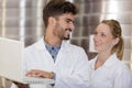 young man and woman wearing labcoats looking at laptop Royalty Free Stock Photo