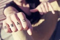 Young man with the word swag tattooed in his fist, with a filter Royalty Free Stock Photo