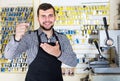 Young man worker displaying result of his key making in workshop Royalty Free Stock Photo