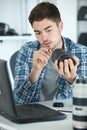 Young man working on camera lens with laptop on desk Royalty Free Stock Photo