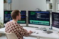 Young Man Working with Code on Multiple Computer Monitors Royalty Free Stock Photo