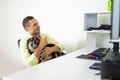 Young man working on computer at home, sitting on chair with his dog Royalty Free Stock Photo