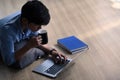 Young man working with computer laptop and drinking coffee while laying on wooden floor . Royalty Free Stock Photo