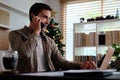 Young man working with computer laptop and talking on mobile phone Royalty Free Stock Photo